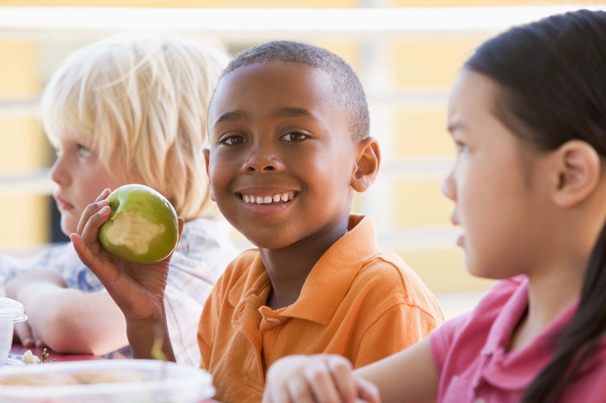 A young boy holds an apple.