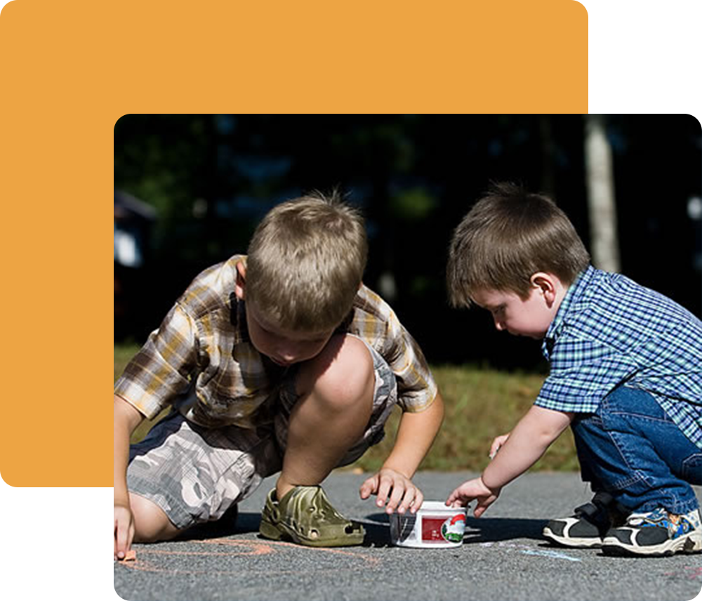 Little boys playing with sidewalk chalk.