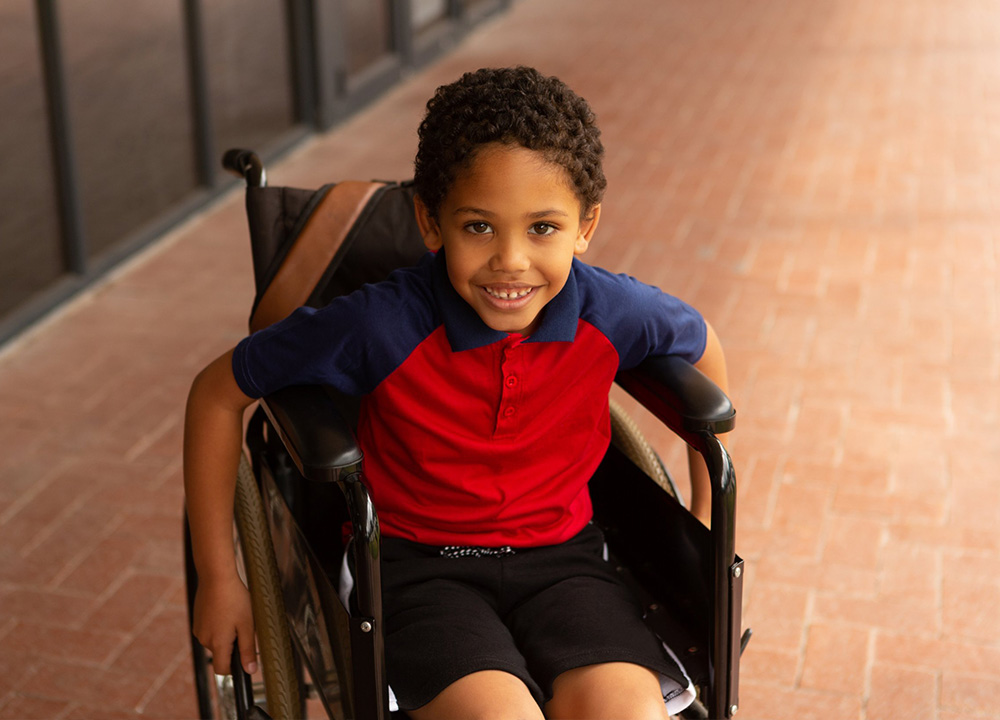 A boy in a wheelchair smiling.
