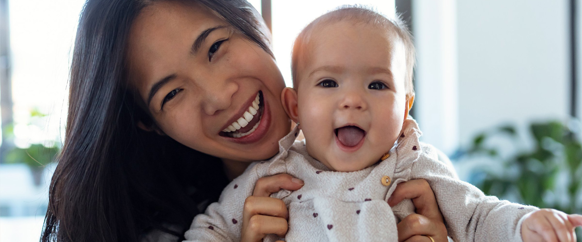 A mom holds her baby and both are smiling