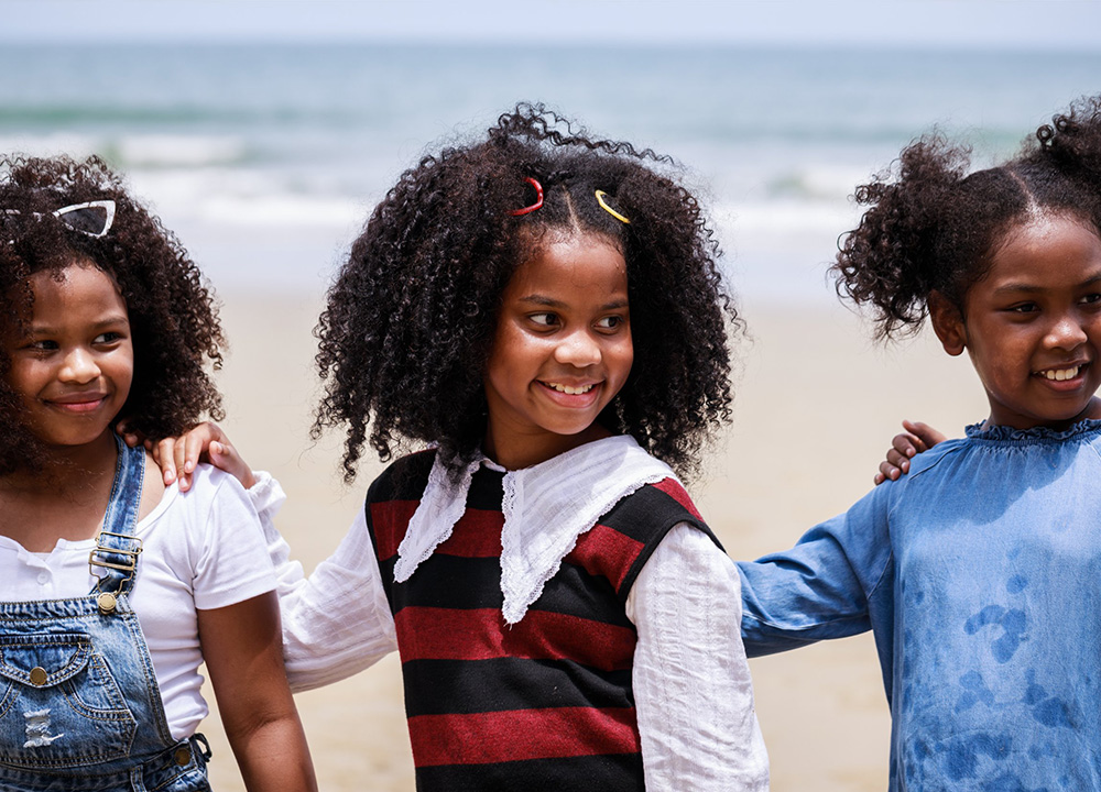 Three girls playing on a beach.
